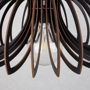 May include: Black wooden pendant light fixture with a circular, open design. The light fixture has a single bulb in the center.