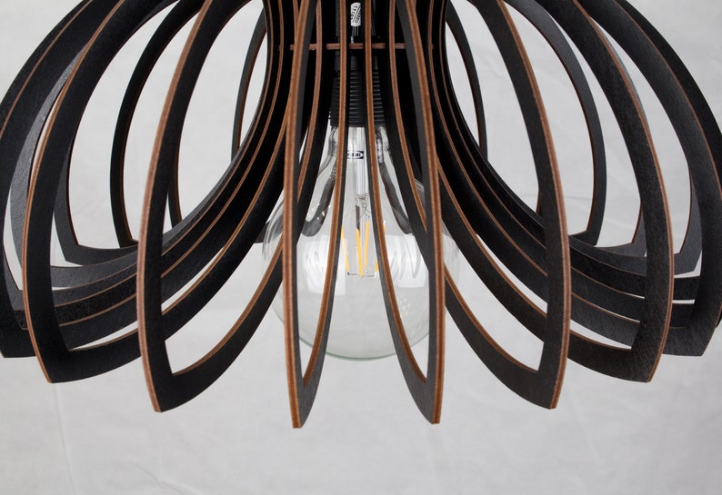 May include: Black wooden pendant light fixture with a circular, open design. The light fixture has a single bulb in the center.