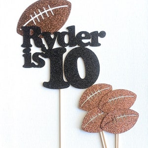 May include: Black and brown glitter cake topper with the text "Ryder is 10" and football designs.