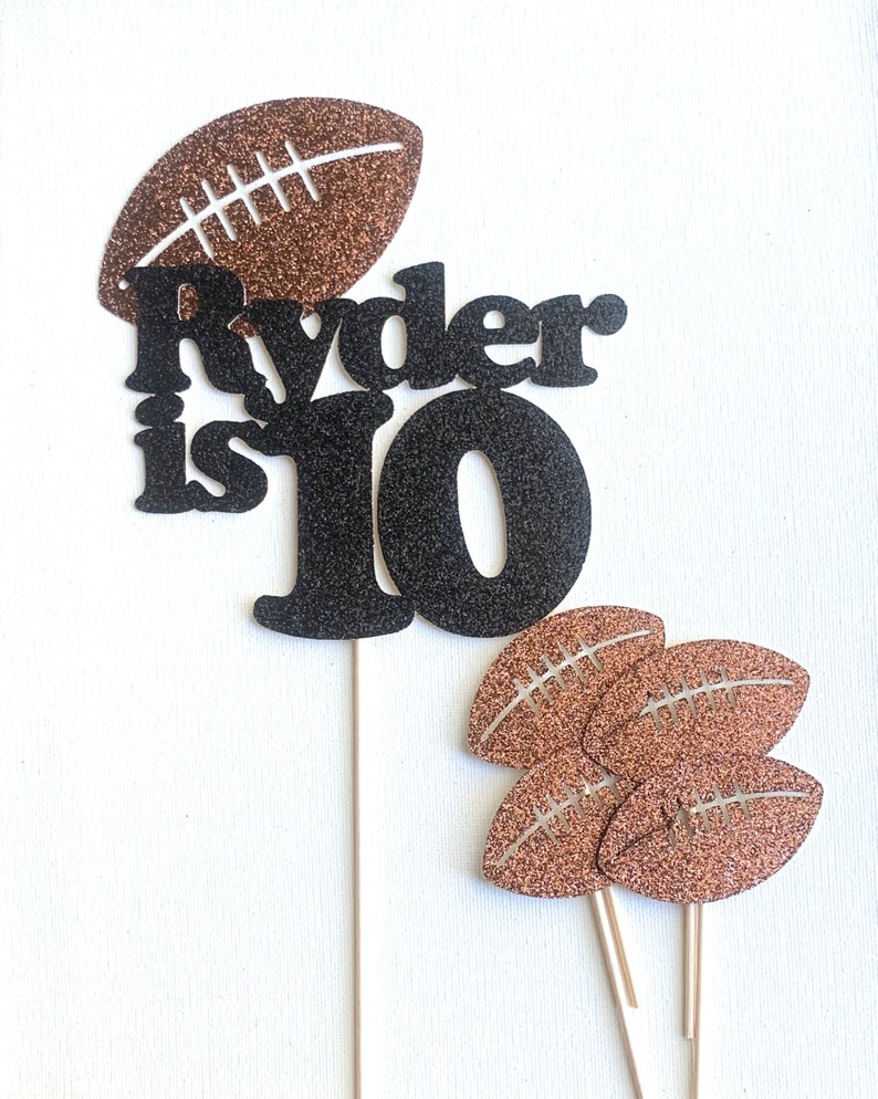 May include: Black and brown glitter cake topper with the text "Ryder is 10" and football designs.