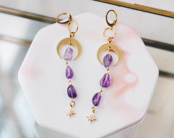 May include: Gold crescent moon earrings with a dangling chain of purple amethyst stones and a star charm at the bottom.