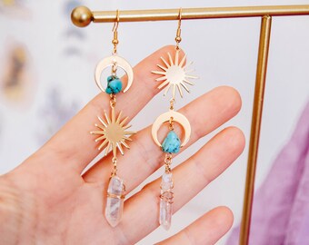 May include: Gold earrings with turquoise stones, crescent moons, and sunburst charms. The earrings are dangling and feature clear quartz crystals at the bottom.