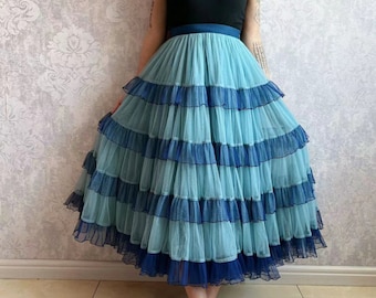 May include: A light blue tulle skirt with multiple layers of ruffles. The skirt has a dark blue trim around each ruffle.