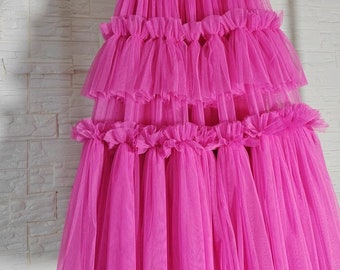 May include: A bright pink tulle skirt with multiple layers of ruffles. The skirt is full and flowing, and it would be perfect for a special occasion.