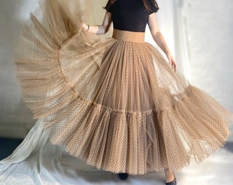 May include: A brown tulle skirt with black polka dots and a brown waistband. The skirt is layered and has a flowing silhouette.