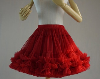 Peut inclure: Une jupon en tulle rouge avec plusieurs couches de volants. Le jupon est sur un mannequin blanc.