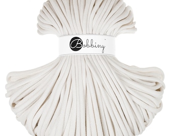 May include: A large spool of off-white cotton cord, wrapped in a circle. The cord is thick and textured. The label on the spool reads "Bobbiny".