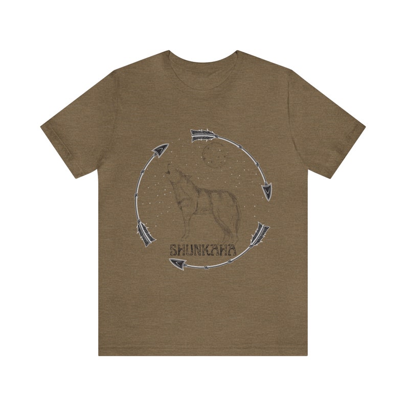 Puede incluir: Una camiseta marr&oacute;n con un lobo aullando a la luna. El lobo est&aacute; rodeado por un c&iacute;rculo de flechas y la palabra "SHUNKARA" est&aacute; escrita debajo del lobo.