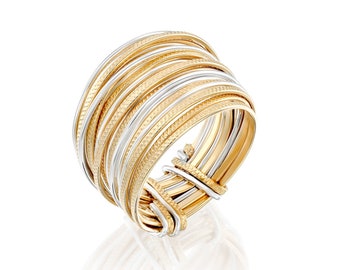 May include: A gold and silver ring with multiple bands intertwined. The bands are textured and have a polished finish.