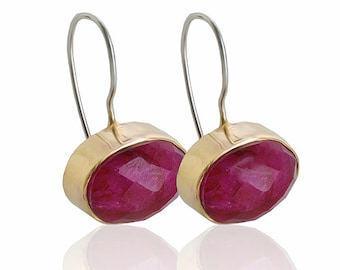 May include: A pair of gold earrings with pink gemstone drops. The earrings have a simple, elegant design.