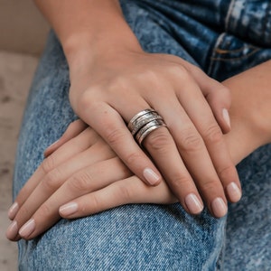 May include: A silver ring with multiple bands stacked on top of each other. The ring is decorated with small, clear stones.