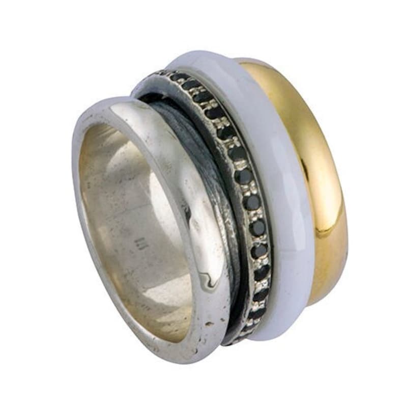 May include: A silver, gold, and white ring with a black stone band. The ring is made of three bands that spin independently.
