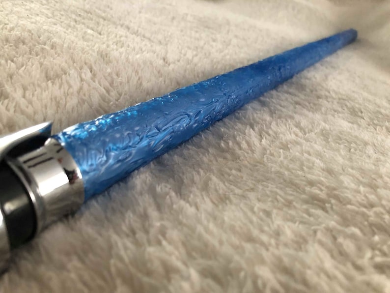 May include: A blue lightsaber with a textured handle and a silver metal hilt.