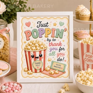May include: A framed print with the words "Just POPPIN'" and a cartoon popcorn bucket. The print is surrounded by popcorn, cookies, and cupcakes. The text on the print says "by to thank you for all you do!" and "You're Awesome!"