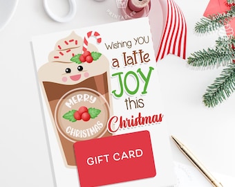 May include: A white card with a red gift card attached. The card features a cartoon latte with a red and white candy cane and the text "Wishing you a latte joy this Christmas".
