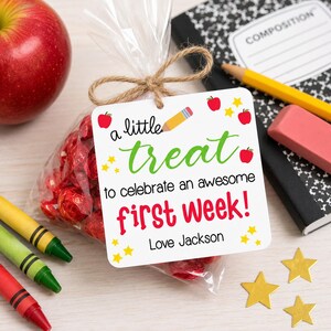 Peut inclure: Un sachet en plastique transparent rempli de bonbons emball&eacute;s en rouge, attach&eacute; avec de la ficelle et une &eacute;tiquette carr&eacute;e blanche. L'&eacute;tiquette porte le texte 'a little treat to celebrate an awesome first week! Love Jackson' avec des pommes rouges.