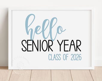 May include: A white framed print with the text "hello senior year class of 2026" in black and blue lettering.