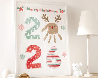May include: A framed wall art print featuring the text Merry Christmas, the number 2, a handprint reindeer illustration, and the number 26. The number 2 has a green tree pattern, the number 2 is red with snowflakes, and the 6 has red and green stripes.