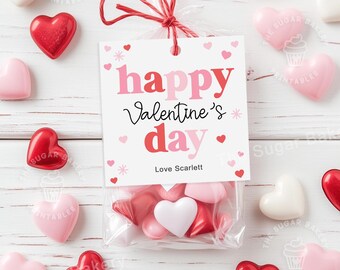 May include: A white gift tag with red and pink text that reads "happy Valentine's day" and "Love Scarlett". The tag is tied with a red ribbon to a clear plastic bag filled with small red, pink, and white heart-shaped candies.