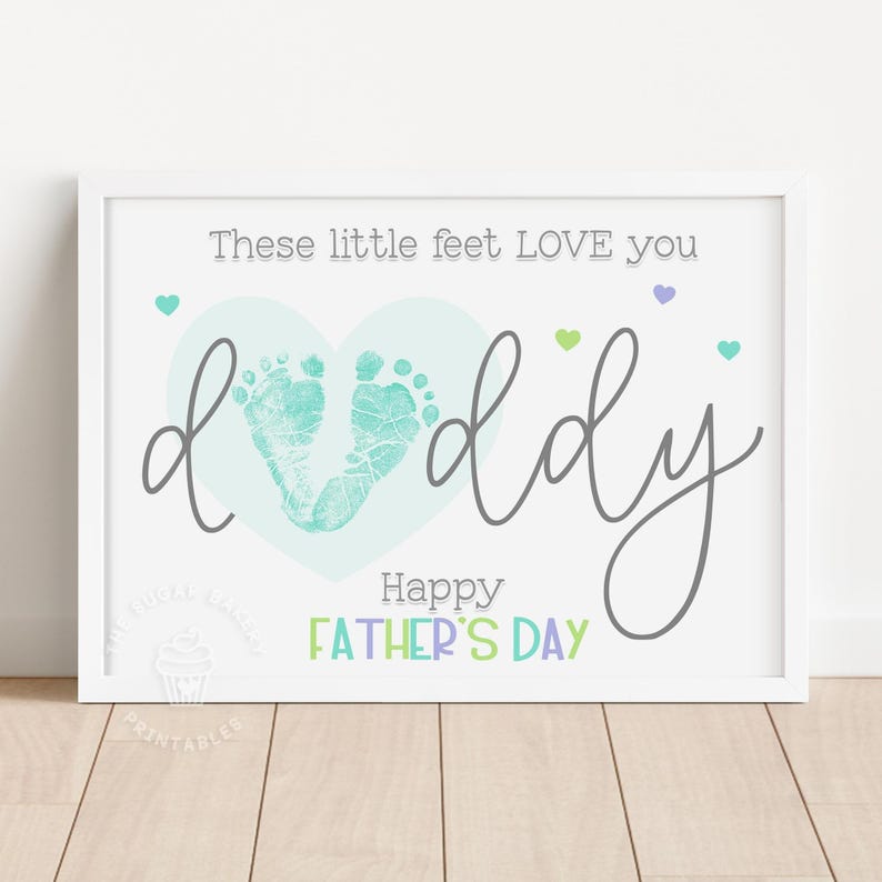 K&ouml;nnte beinhalten: Eine druckbare Vatertagskarte mit einem blauen Herzen und zwei Baby-Fu&szlig;abdr&uuml;cken darin. Der Text lautet "Diese kleinen F&uuml;&szlig;e LIEBEN dich Papa Frohen Vatertag".