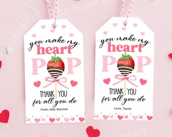 Könnte beinhalten: Zwei weiße Geschenkanhänger mit rosa Herzen und dem Text "You make my heart pop" mit einer Schokoladen-Erdbeere auf einem Stiel. Ein Anhänger sagt "Thank you for all you do" und der andere sagt "Thank you for all you do".