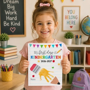 May include: A white rectangular sign with lined paper background featuring the text My first day of KINDERGARTEN 2026-2027. The design includes colorful bunting, a pencil, apples, stars, a heart, and a large yellow handprint graphic with a pencil tip.