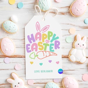 Pu&ograve; includere: Un'etichetta bianca stampabile con un messaggio di Buona Pasqua colorato e un design a forma di orecchie di coniglio. L'etichetta include anche una carota e cuori. Il testo "Love Benjamin" &egrave; in fondo all'etichetta.