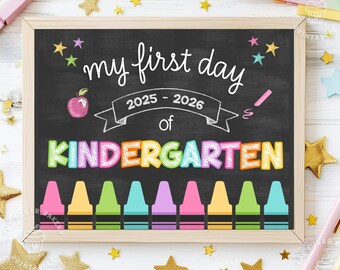 May include: A black chalkboard with the text "my first day of KINDERGARTEN" in colorful letters. The year 2025-2026 is written in white. There are colorful crayons and stars on the chalkboard.