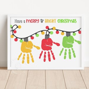 Puede incluir: Una impresión enmarcada con el texto "Have a MERRY & BRIGHT CHRISTMAS". La obra presenta bombillas con forma de huellas de manos en amarillo, rojo y verde, conectadas por un cable negro con bombillas de colores. La impresión está sobre un fondo blanco.