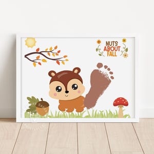 May include: A framed print featuring a cartoon squirrel, acorn, and mushroom on a white background. The text "Nuts About Fall" is displayed above a brown footprint. A sun and fall leaves are also included.
