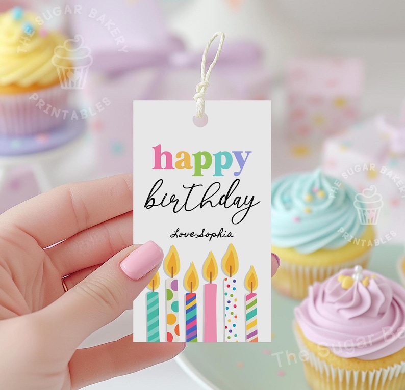 May include: A colorful happy birthday gift tag with a string for hanging. The tag features a rainbow-colored "happy birthday" message and a row of colorful candles with confetti.