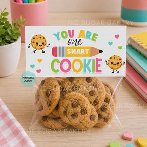 May include: A transparent bag of chocolate chip cookies. A card with the text "You are one smart cookie" is attached. The card features cartoon cookies, a pencil, and colourful hearts. The image is from The Sugar Bakery.