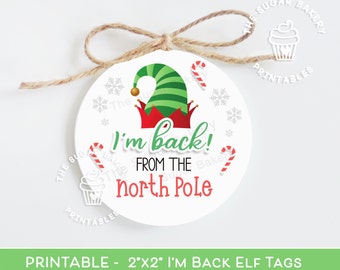 May include: A white round printable gift tag with a green elf hat, red candy canes, and snowflakes. The text on the tag reads "I'm back! From the North Pole".
