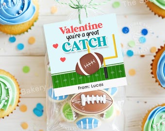 May include: A Valentine's Day gift bag with a blue and green football-themed tag that reads "Valentine you're a great CATCH" and "From: Lucas". The bag contains cookies decorated with footballs.