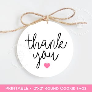 Pode incluir: Etiquetas redondas para biscoitos imprimíveis com o texto "obrigado" em letra cursiva preta e um pequeno coração rosa. As etiquetas têm um diâmetro de 5 cm.