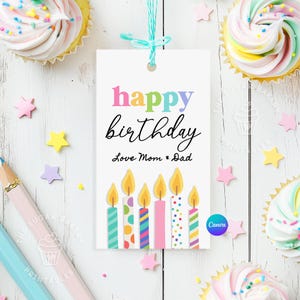 May include: A white gift tag with the text "happy birthday" in rainbow colors and "Love Mom & Dad" in black. The tag features six colorful candles with flames.