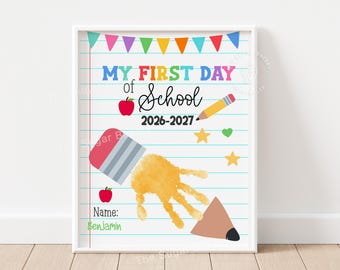 May include: A framed poster featuring a lined paper background with colorful bunting at the top. The text reads MY FIRST DAY of School 2026-2027. It includes a red apple, a yellow pencil, stars, a heart, and a yellow handprint graphic with the name Benjamin.