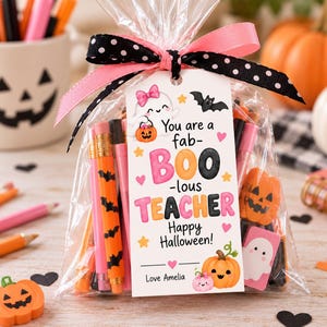May include: A clear plastic gift bag filled with orange and pink pencils and pumpkin-shaped erasers, tied with a black and white polka dot ribbon and a pink ribbon. A white tag reads: You are a fab-BOO-lous TEACHER Happy Halloween! Love Amelia.