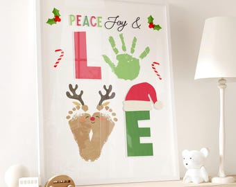 May include: A framed Christmas-themed print with the words "PEACE Joy & LOVE" in colorful letters. The "L" is red, the "E" is green, and the "O" is a handprint. The "V" is a reindeer made of footprints, and the print includes candy canes and holly.