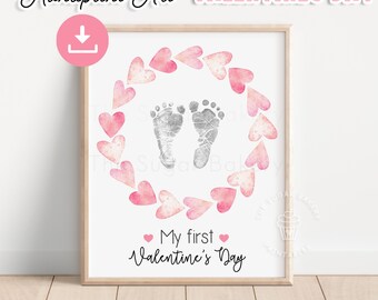 Könnte beinhalten: Ein druckbares Valentinstags-Handabdruck-Kunstdesign mit einem Kranz aus rosa Aquarellherzen, in dem sich ein Baby-Fußabdruck befindet. Der Text "My first Valentine's Day" steht unter dem Fußabdruck.