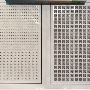 May include: Two rectangular sheets of adhesive labels with black borders. The left sheet contains numerous small, square white stickers with tiny black icons. The right sheet features a grid of small, square black and white QR code stickers.
