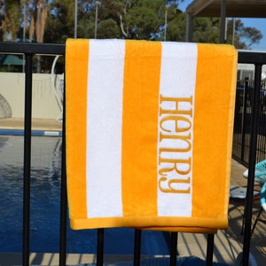 May include: A yellow and white striped beach towel with the name "Henry" embroidered in yellow on the towel.