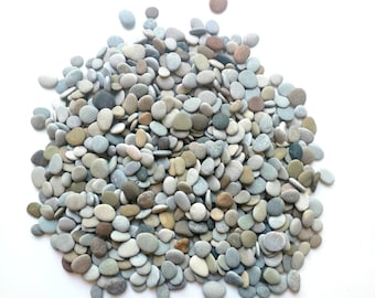 Puede incluir: Un montón grande de piedras lisas de color gris, marrón y blanco. Las piedras son de varios tamaños y formas, y están dispuestas en un patrón aleatorio.