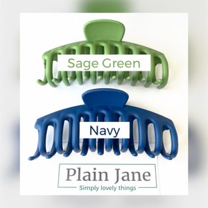 Puede incluir: Dos grandes pinzas para el pelo de pl&aacute;stico, una verde salvia y otra azul marino. Las pinzas est&aacute;n dise&ntilde;adas con m&uacute;ltiples dientes para sujetar el cabello de forma segura. El texto "Sage Green" est&aacute; impreso en la pinza verde y "Navy" est&aacute; impreso en la pinza azul. El texto "Plain Jane Simply lovely things" est&aacute; impreso debajo de las pinzas.