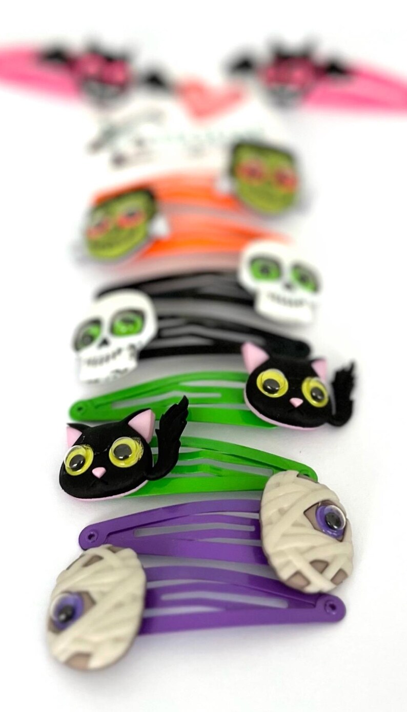 Pode incluir: Um conjunto de dez presilhas de cabelo com tema de Halloween. As presilhas apresentam v&aacute;rios designs, incluindo uma caveira, um gato, uma m&uacute;mia e um fantasma. As presilhas s&atilde;o feitas de pl&aacute;stico e t&ecirc;m um design colorido.