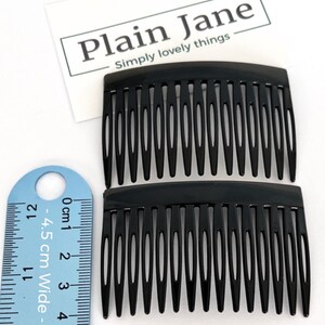 May include: Two black hair combs with fine teeth, next to a ruler showing a width of 4.5 cm. The combs are made of a glossy material. The text "Plain Jane Simply lovely things" is visible in the background.