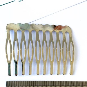May include: A silver metal hair comb with seven teeth. The comb is approximately 2 inches long.