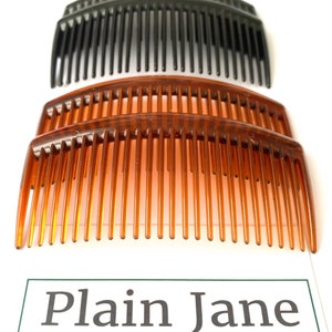May include: Three hair combs, two brown and one black, are stacked on top of each other. The combs are curved and have a wide tooth design.