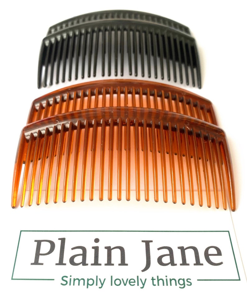 May include: Three hair combs, two brown and one black, are stacked on top of each other. The combs are curved and have a wide tooth design.