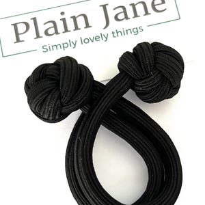 Può includere: Due fermagli per cravatta in tessuto nero con estremità annodate. Plain Jane Simply lovely things.